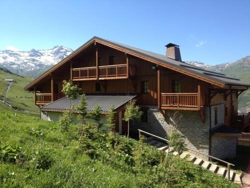 une maison sur une colline avec des montagnes en arrière-plan dans l'établissement CGH Résidences & Spas les Chalets du Soleil Authentiques, aux Menuires