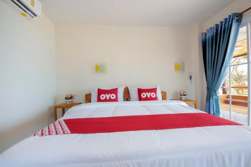 ein Schlafzimmer mit einem weißen Bett mit zwei roten Kissen in der Unterkunft OYO 1085 Ma Lanta House in Ko Lanta