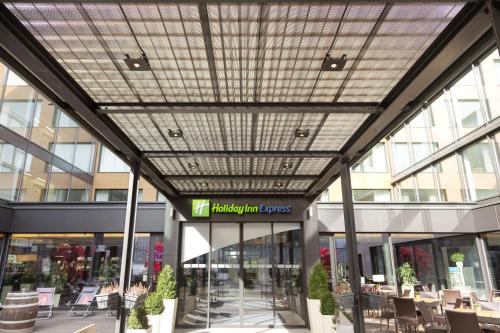 a glass ceiling in a building with tables and chairs at Holiday Inn Express Zürich Airport by IHG in Rümlang