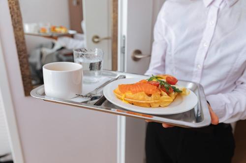 a man holding a tray with a plate of food at Art Deco Central Rooms in Lviv