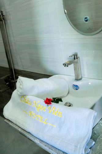 a bathroom sink with towels and a red rose on it at Châu Ngọc Viên Hotel - Biển Mỹ Khê - Quảng Ngãi in Quang Ngai