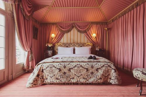 a bedroom with a large bed with red curtains at L'Hôtel in Paris