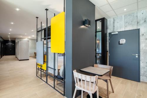 a dining room with a table and a yellow wall at B&B HOTEL Saint-Denis Porte de Paris in Saint-Denis