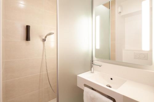 uma casa de banho com um chuveiro, um lavatório e um espelho. em B&B HOTEL Saint-Denis Porte de Paris em Saint-Denis