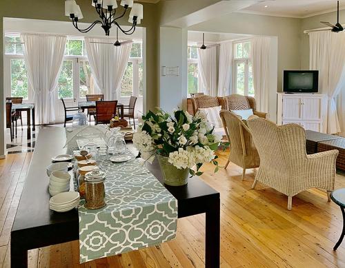 a living room with a table with flowers on it at Coral Tree Colony Bed & Breakfast in Southbroom