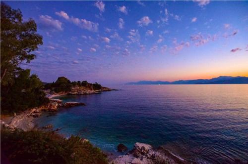 uma vista para um corpo de água com um pôr-do-sol em Poseidon Hotel em Kassiopi
