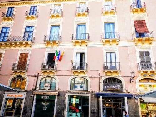 a pink building in paris with flags on it at Meo Design Suites & Spa in Catania