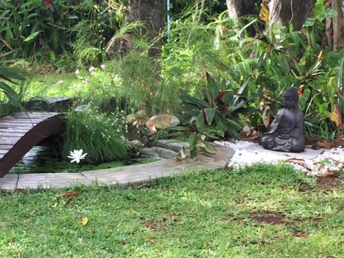 a statue sitting on the grass next to a bridge at La Case O zoizos in Saint-Joseph