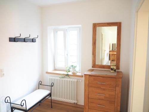 a bathroom with a dresser and a mirror and a chair at Ferienwohnungen Grüner Baum in Seinsheim