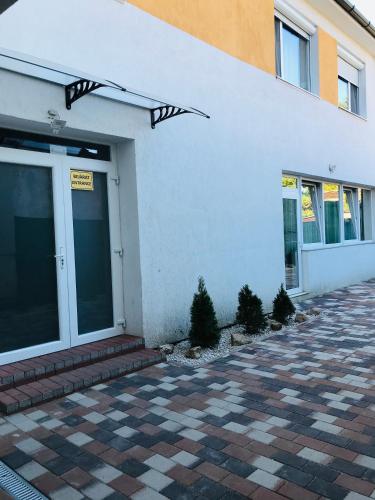 a white building with a door and some plants at Mira apartman in Debrecen