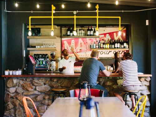un grupo de personas sentadas en un bar en PitStop Lodge, en Gordonʼs Bay