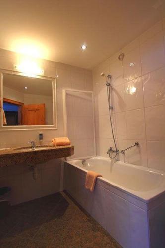 a bathroom with a tub and a sink and a mirror at Appartementhaus Seehof in Kirchberg in Tirol