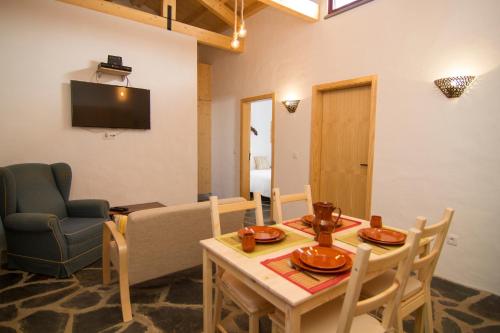 a living room with a table and chairs and a television at Casa da Orada in Outeiro
