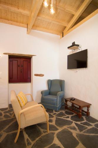 a living room with a couch and a chair and a tv at Casa da Orada in Outeiro