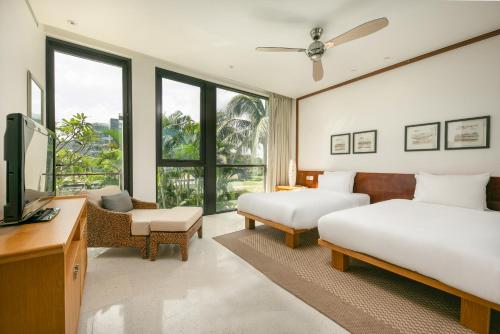 a hotel room with two beds and a television at Abogo Resort Villas Beachview Da Nang in Danang