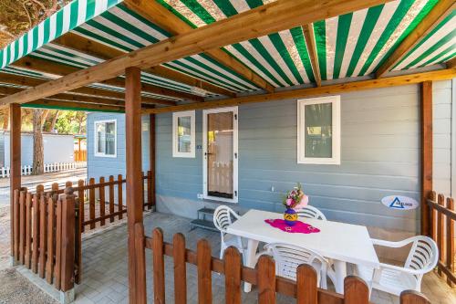 a covered porch with a white table and chairs at Rivaverde Family Camping Village in Marina di Ravenna