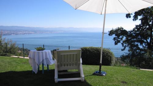 a table and a chair under an umbrella at Apartments Villa Krasa in Lovran