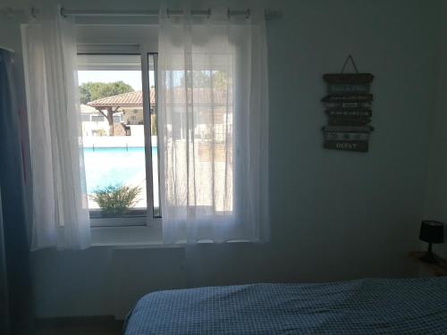 a bedroom with a window with a view of a pool at Gîte l'Escapade au bassin d'Arcachon à Biganos in Biganos