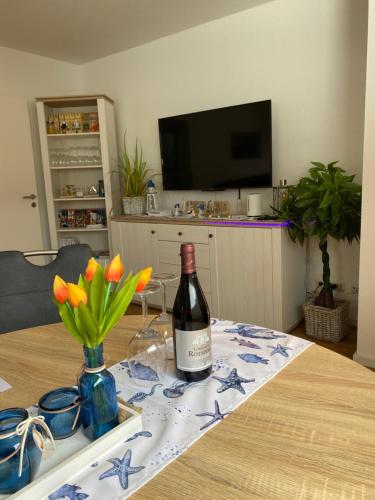 a bottle of wine sitting on a table with flowers at Luxuriöses Ferienhaus Anita nahe Timmendorfer Strand, Travemünde und Lübeck in Sereetz