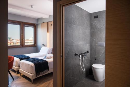 a bedroom with two beds and a shower and a bathroom at B&B Hotel Milano City Center Duomo in Milan