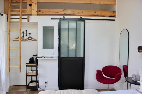 Zimmer mit einer schwarzen Tür und einem roten Stuhl in der Unterkunft Le Chemin du Village in Croth