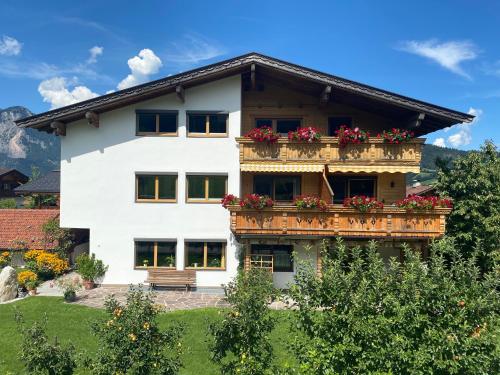 a white house with a balcony with red flowers at Haus Sylvia in Reith im Alpbachtal