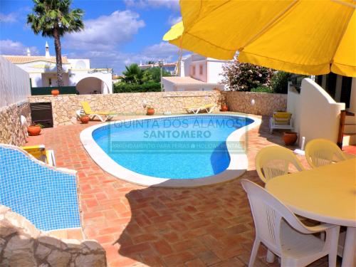 a swimming pool with chairs and a table and a yellow umbrella at Villa Catuna - Quinta do Jolu in Guia