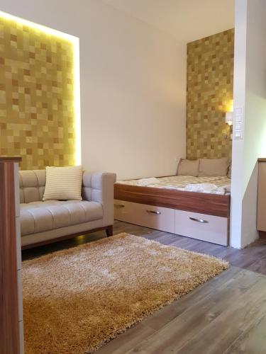 Habitación con cama, sofá y espejo. en Embassy Studio Apartment Citypark, en Budapest