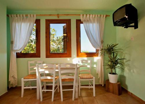 comedor con mesa, sillas y ventanas en Victoria's Guesthouse, en Damouchari