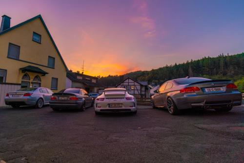 a group of cars parked in a parking lot at sunset at North Loop Rooms in Adenau