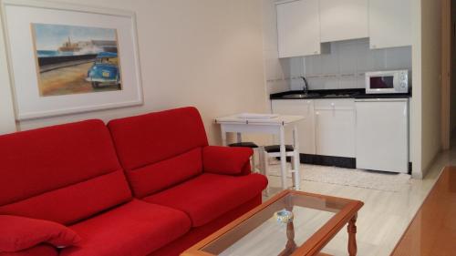 a living room with a red couch and a kitchen at Apartamentos Maritimo Suites-Solo Adultos in O Grove