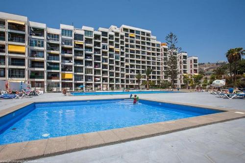 プラヤ・デ・ラス・アメリカスにあるEnjoy the sea and pool in Playa de las Americasの大きなアパートメントの建物の前にスイミングプールがあります。