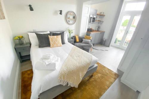 a white bedroom with a large bed and a chair at The Hideaway in Folkestone