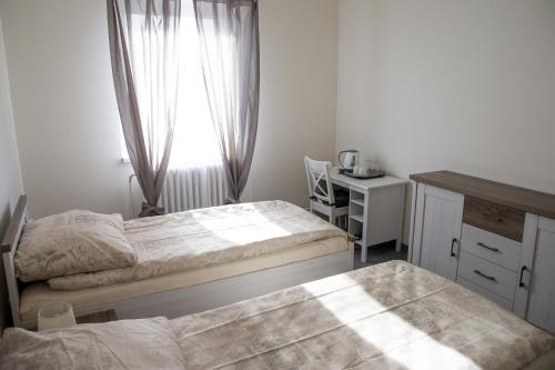 a bedroom with two beds and a desk and a window at Penzion 68 in Kladno