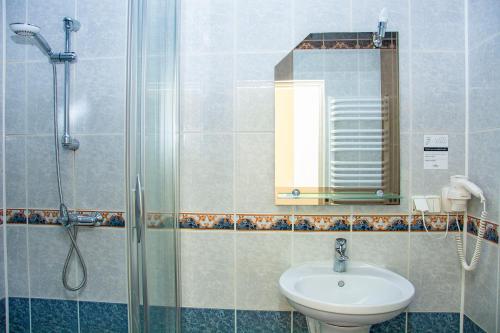 a bathroom with a sink and a shower with a mirror at Savoy in Spała