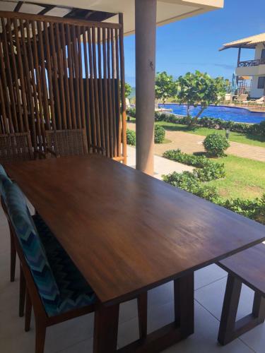 a wooden table and chairs with a view of the ocean at Itacimirim boulevard in Itacimirim