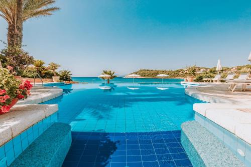 a swimming pool with blue water and palm trees at Hotel La Bitta - Bovis Hotels in Àrbatax