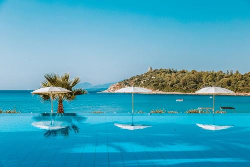 a swimming pool with umbrellas and the ocean at Hotel La Bitta - Bovis Hotels in Àrbatax