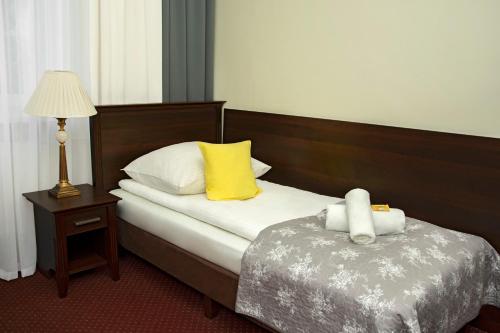 a hotel room with a bed with a yellow pillow at Savoy in Spała