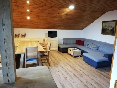 a living room with a blue couch and a table at Stockachhof in Fügenberg