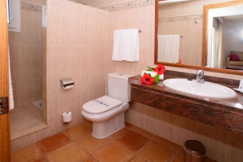 
a bathroom with a toilet a sink and a mirror at Cala Llenya Resort Ibiza in Cala Llenya
