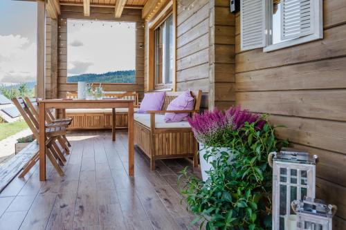 a porch with a table and chairs on a wooden wall at Sielska Chyża in Rzepedż
