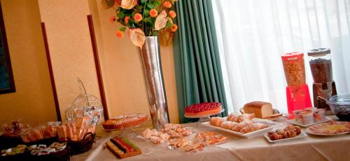 a table with food and a vase with flowers on it at Aerhotel Phelipe in SantʼEufemia Lamezia