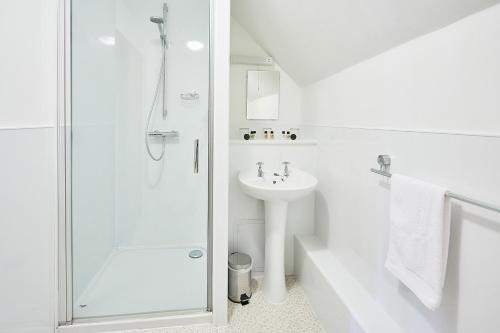 baño blanco con ducha y lavamanos en The Bateman Arms at Shobdon, en Shobdon