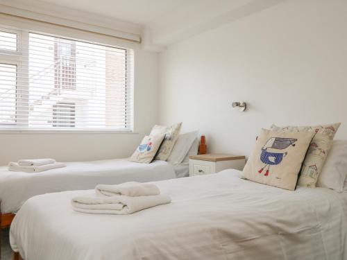 una camera da letto con due letti con lenzuola bianche e una finestra di 2 Europa Court a Newquay