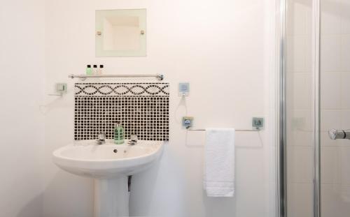 a white bathroom with a sink and a shower at The Heart of Summertown - Bright & Spacious 3BDR Home with Garden in Oxford