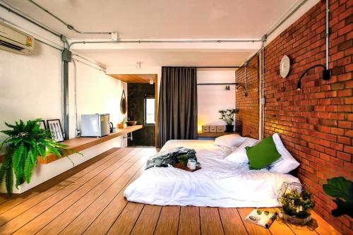 Un dormitorio con dos camas y una pared de ladrillo. en Hidden Habitat - Design Guesthouse, en Bangkok