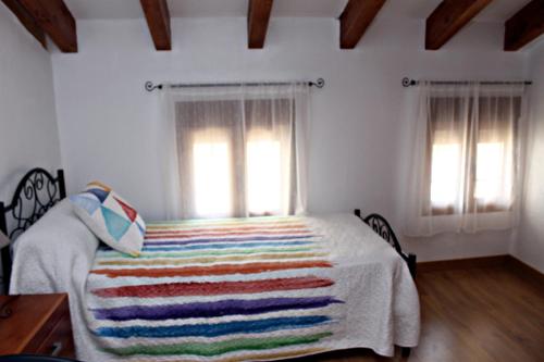 a bedroom with a bed with a colorful blanket on it at Casa Rural Rectoría de Raspay in Raspay