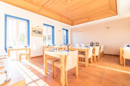 a dining room with tables and chairs and windows at HOTEL LOUSAL Grandola in Lousal