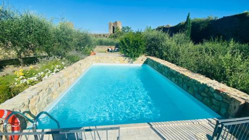 einen Pool in einem Garten mit einer Steinmauer in der Unterkunft Romantik Hotel Monteriggioni in Monteriggioni